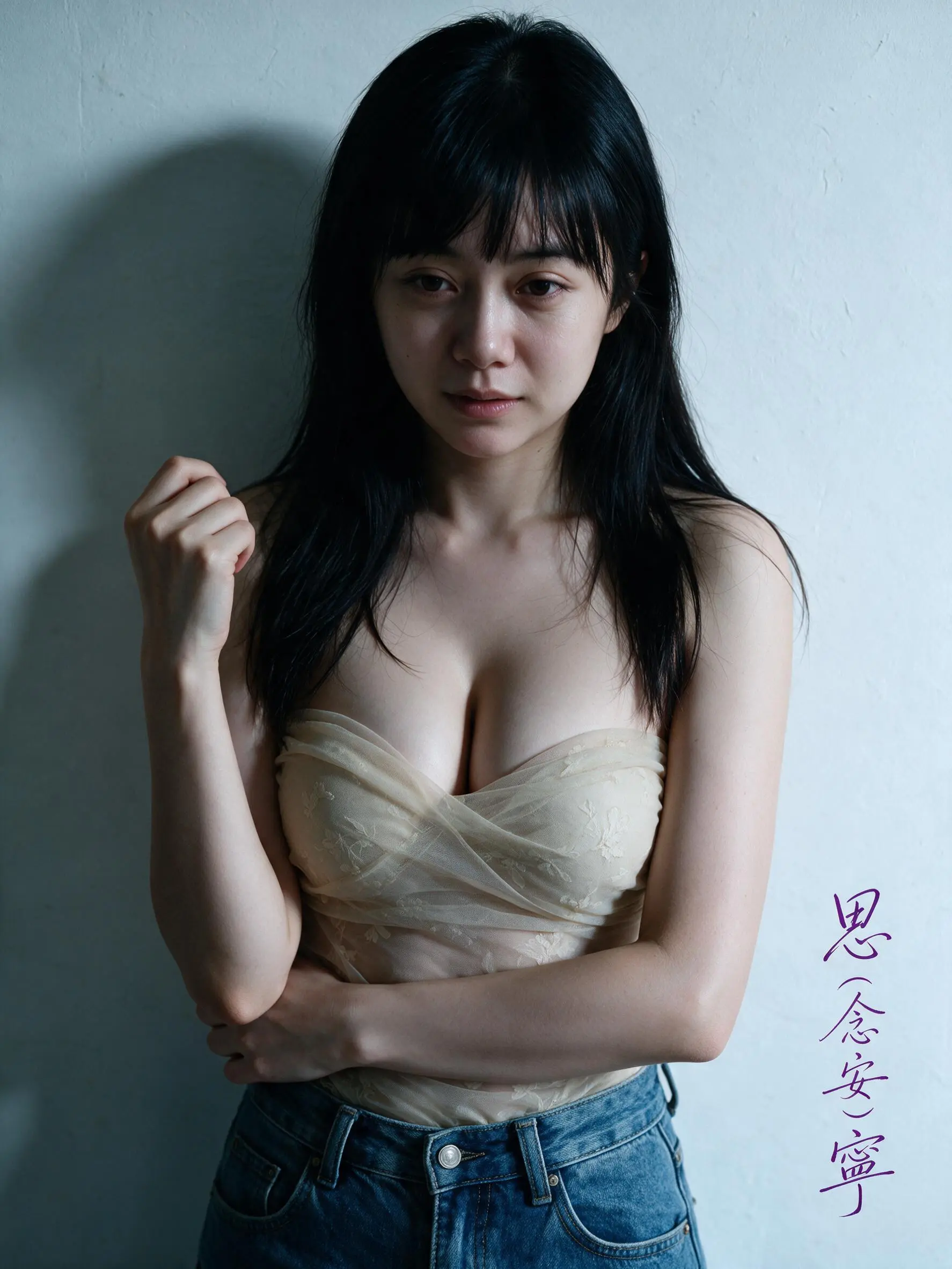 一位年輕的亞洲女子，長髮黑髮，膚色白皙，站在一面樸素的白牆前，右手握拳靠近肩膀，左臂交叉放在腹部，穿著薄紗材質抹胸,胸部